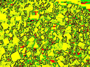 Fotografía intervenida con fuerte pixelado en amarillo, verde y rojo: textura abstracta de una superficie rocosa o mineral.