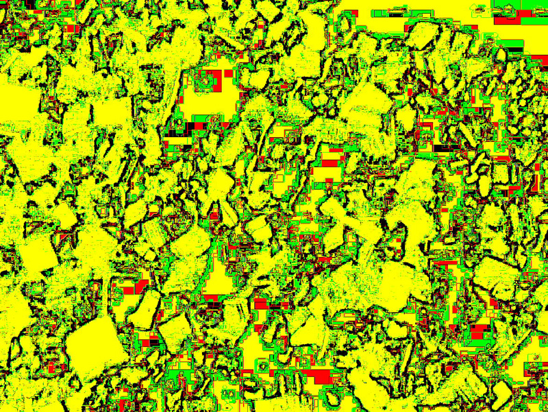 Fotografía intervenida con fuerte pixelado en amarillo, verde y rojo: textura abstracta de una superficie rocosa o mineral.